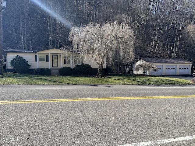 view of front facade featuring a front lawn, a detached garage, and an outdoor structure