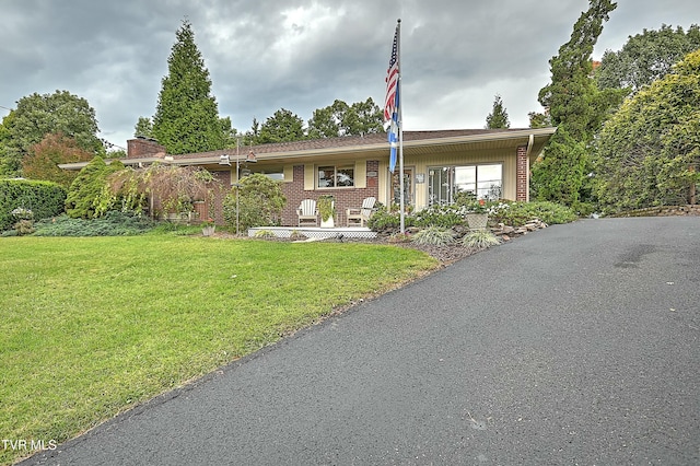 view of front facade featuring a porch, a front yard, and brick siding