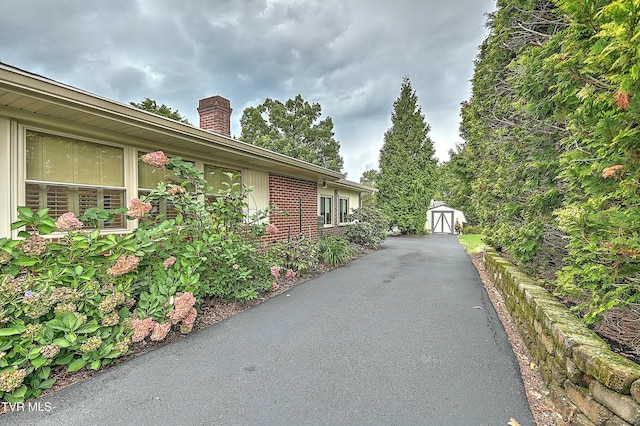 view of side of property with an outbuilding, brick siding, and a chimney