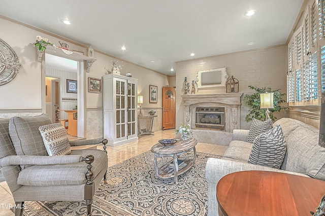 living area with ornamental molding, a glass covered fireplace, wainscoting, and recessed lighting