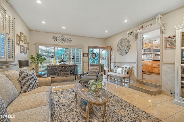 living room featuring a wainscoted wall, plenty of natural light, crown molding, and light tile patterned flooring