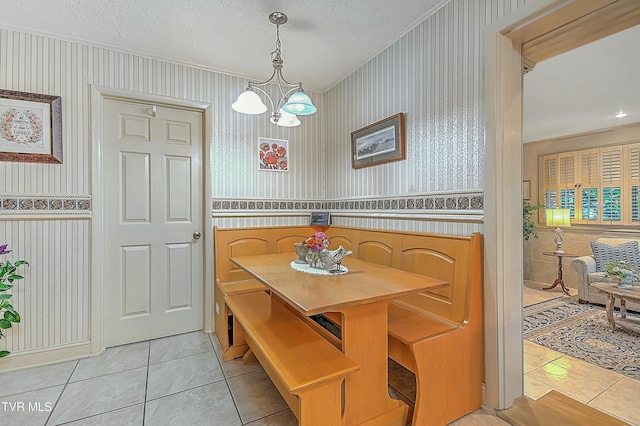 dining room featuring wainscoting, a textured ceiling, and wallpapered walls