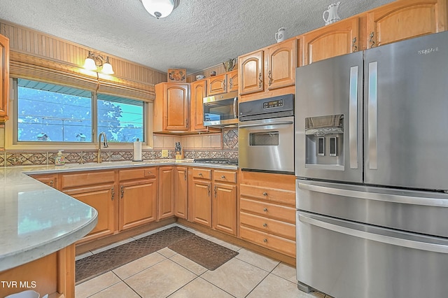 kitchen with light tile patterned floors, light countertops, appliances with stainless steel finishes, and a sink