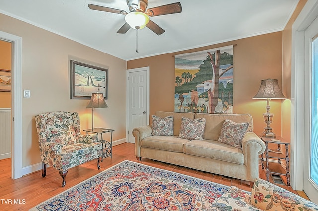 living room featuring ceiling fan, ornamental molding, wood finished floors, and baseboards