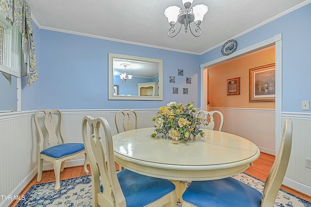 dining room with a chandelier, wood finished floors, and wainscoting