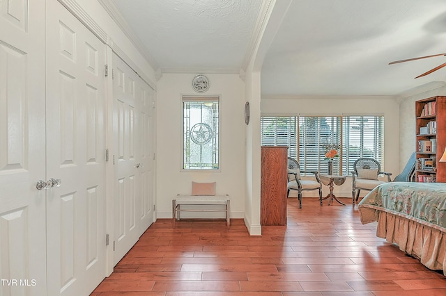 bedroom with ornamental molding, a ceiling fan, baseboards, and wood finished floors