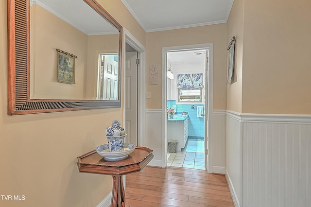 corridor featuring a wainscoted wall, ornamental molding, and wood finished floors