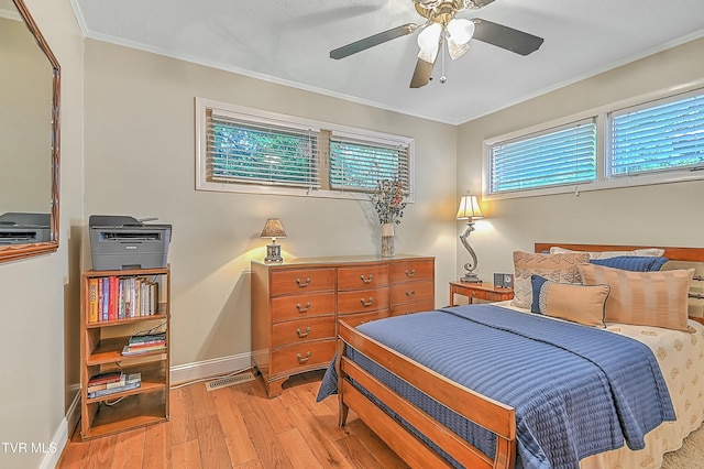 bedroom with light wood finished floors, visible vents, ornamental molding, ceiling fan, and baseboards