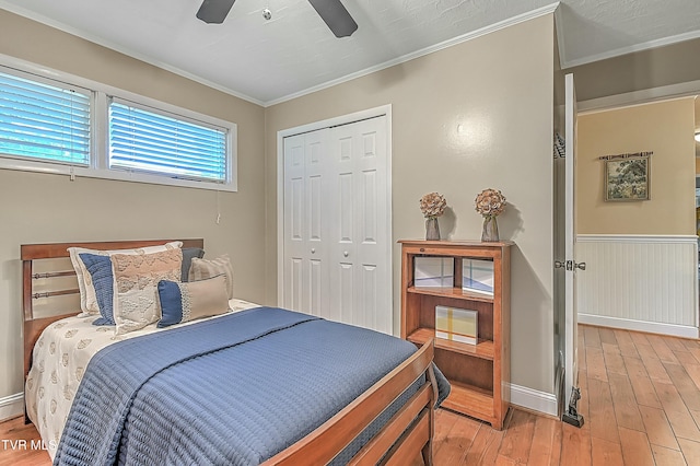 bedroom featuring crown molding, a closet, a ceiling fan, light wood-type flooring, and baseboards