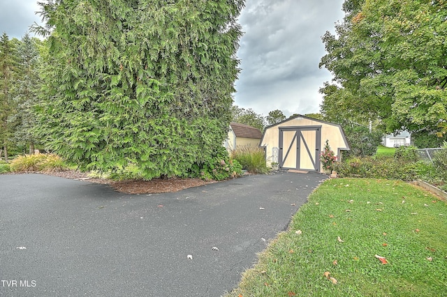 view of gate with a storage unit, a lawn, and an outdoor structure