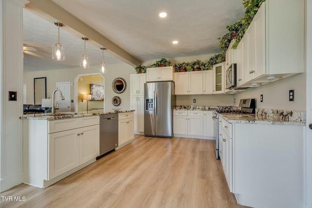 kitchen featuring light stone counters, light wood-style flooring, a sink, white cabinets, and appliances with stainless steel finishes