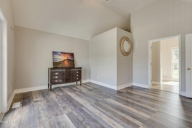 unfurnished room featuring lofted ceiling, baseboards, and wood finished floors