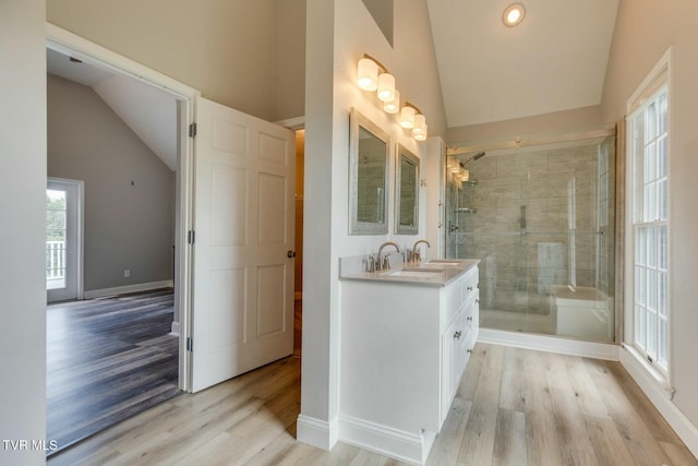 bathroom featuring a stall shower, baseboards, wood finished floors, vaulted ceiling, and vanity