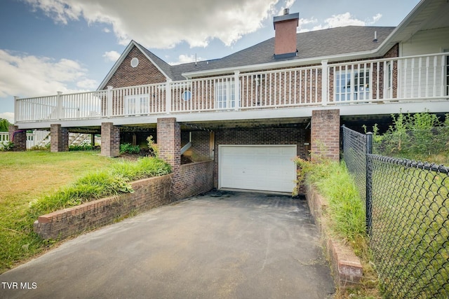 rear view of house featuring brick siding, fence, driveway, a lawn, and a chimney