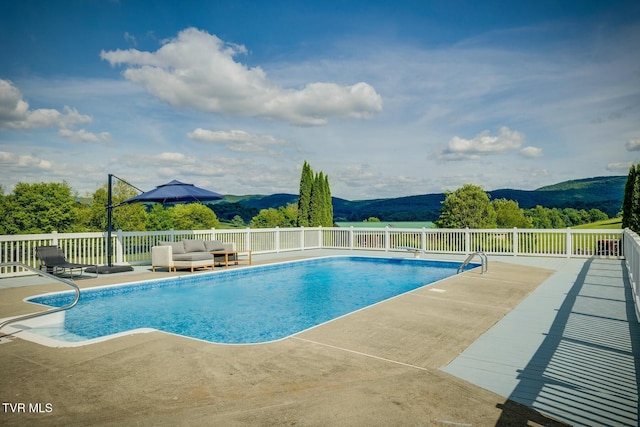 view of pool featuring a mountain view, an outdoor living space, a fenced in pool, and a patio