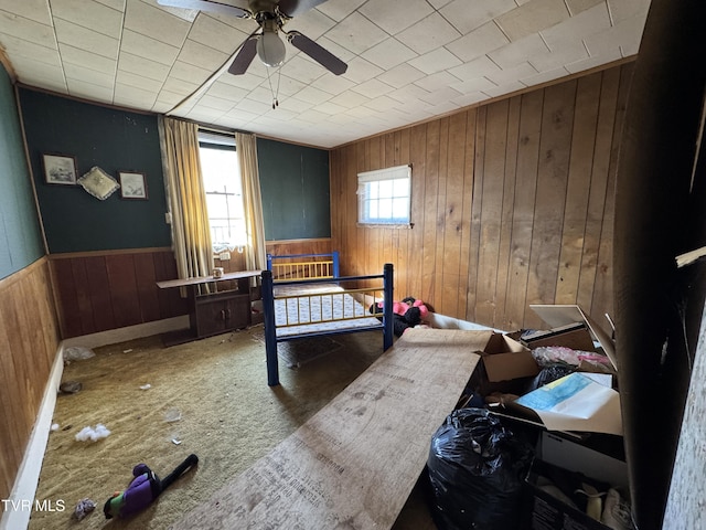 bedroom featuring a wainscoted wall, ceiling fan, and wooden walls