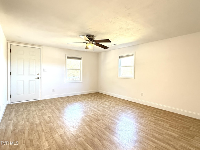 empty room with baseboards, plenty of natural light, visible vents, and wood finished floors