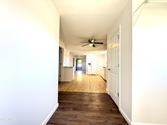 hallway featuring dark wood-type flooring and baseboards