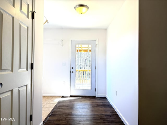 doorway featuring baseboards and dark wood-type flooring