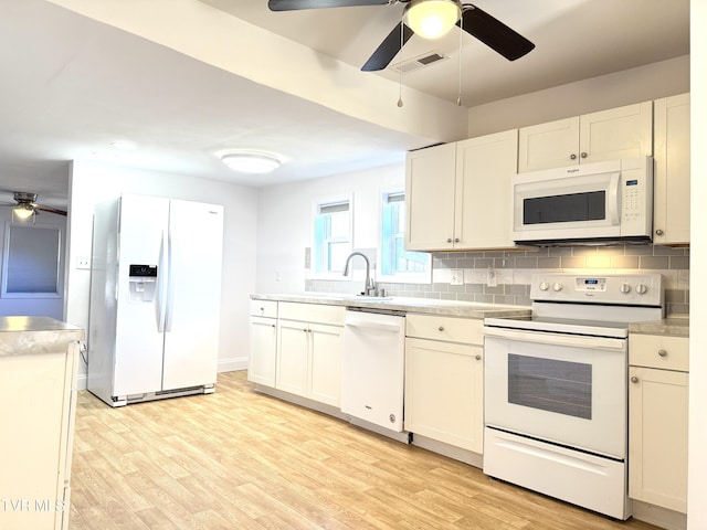 kitchen featuring light wood-style flooring, white appliances, a sink, visible vents, and tasteful backsplash