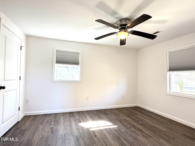 empty room with dark wood-style floors, visible vents, baseboards, and a ceiling fan