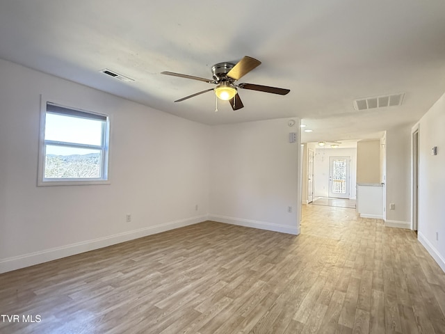 spare room featuring light wood-style flooring, visible vents, and baseboards