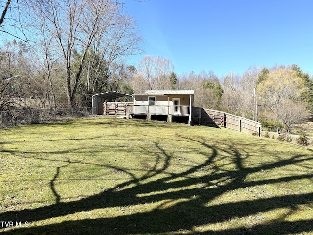 view of yard with a detached carport, fence, and a wooden deck