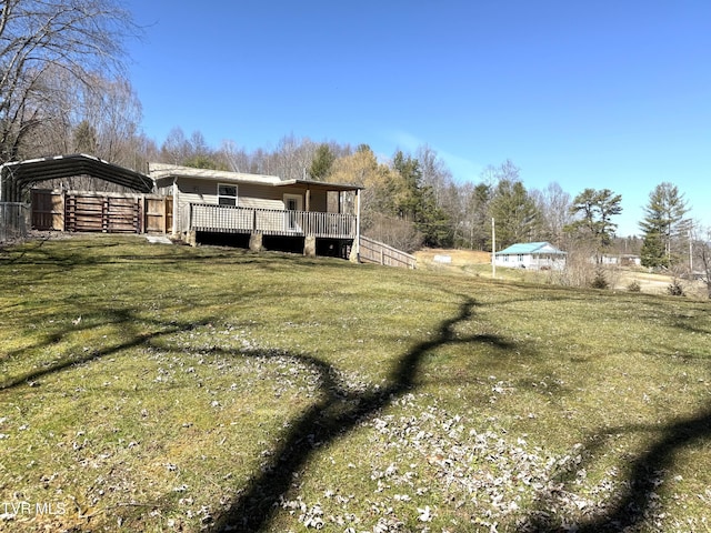 view of side of home with a deck, a yard, and a detached carport