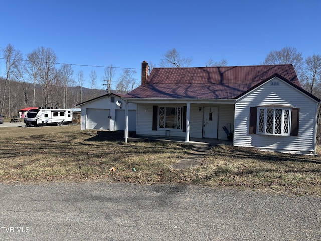 single story home with covered porch, a chimney, and a garage