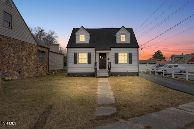 new england style home featuring a shingled roof and a front yard