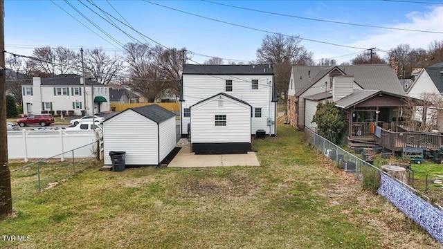 back of property featuring a lawn, an outdoor structure, a fenced backyard, and a residential view