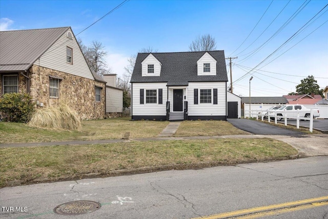 cape cod-style house with roof with shingles and a front lawn