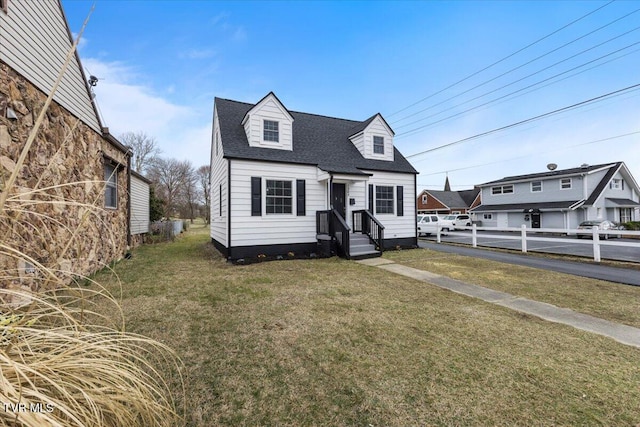 new england style home with roof with shingles and a front yard