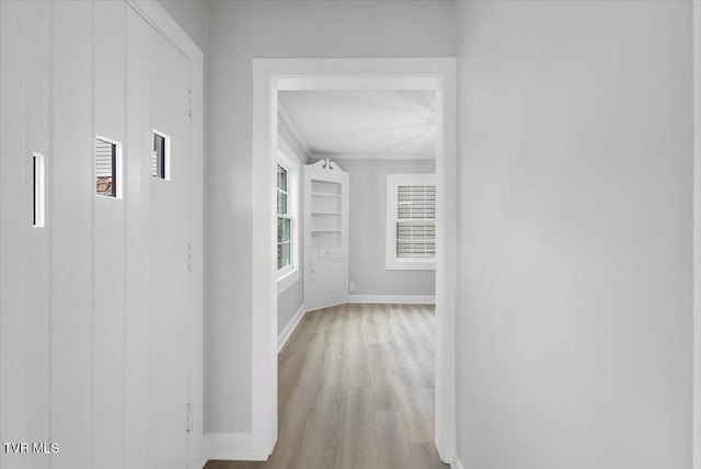 hallway with baseboards, wood finished floors, and ornamental molding