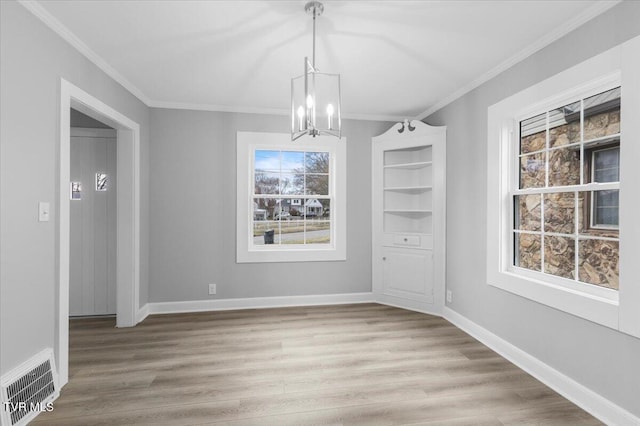 unfurnished dining area with visible vents, crown molding, baseboards, and wood finished floors