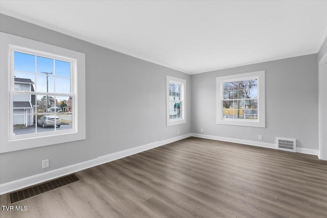 unfurnished room with dark wood-type flooring, visible vents, and baseboards