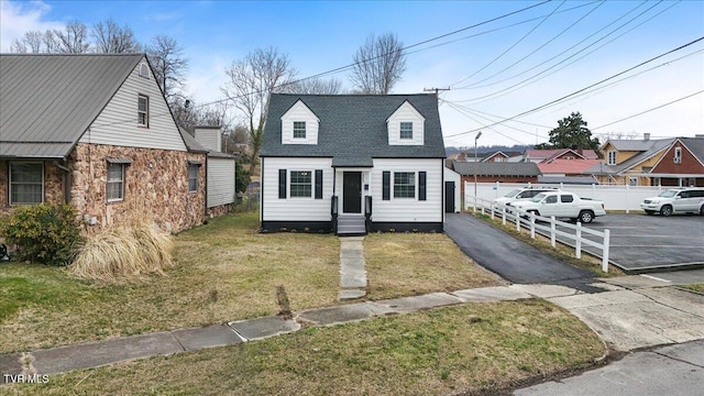 view of front facade with entry steps, a shingled roof, fence, and a front yard