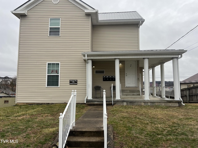 view of front facade with a porch, a front yard, and metal roof