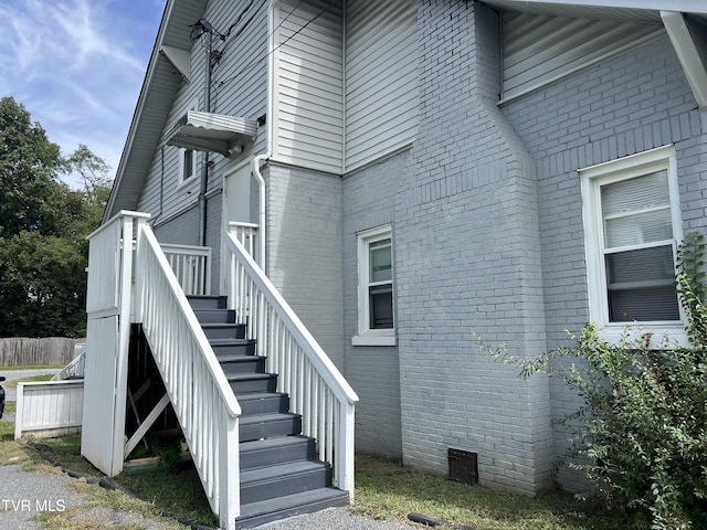 view of side of home with stairway and brick siding