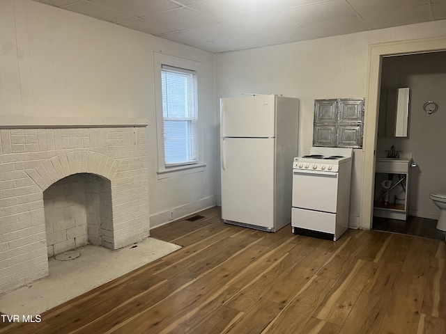 kitchen featuring white appliances, visible vents, wood-type flooring, light countertops, and a sink