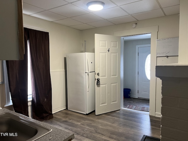 kitchen featuring dark wood-type flooring, freestanding refrigerator, a drop ceiling, and a sink