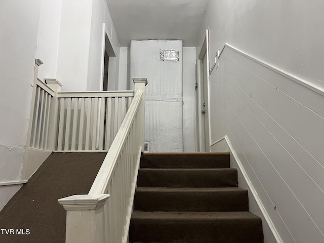 stairway with a wainscoted wall