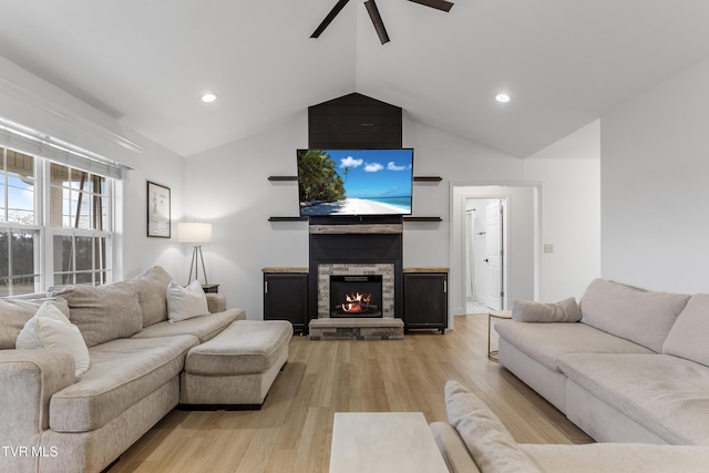 living room featuring lofted ceiling, light wood-style floors, recessed lighting, and a stone fireplace