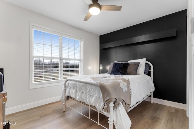 bedroom featuring a ceiling fan, baseboards, and wood finished floors