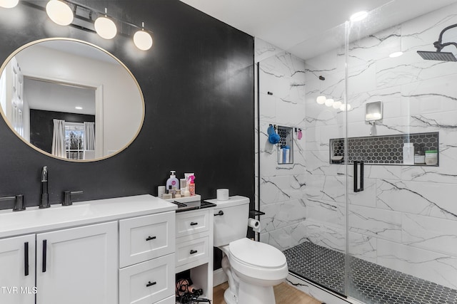 bathroom with a marble finish shower, vanity, and toilet