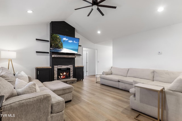 living room featuring recessed lighting, vaulted ceiling, a stone fireplace, ceiling fan, and light wood-type flooring