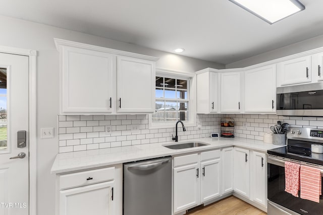 kitchen with stainless steel appliances, white cabinetry, a sink, and decorative backsplash