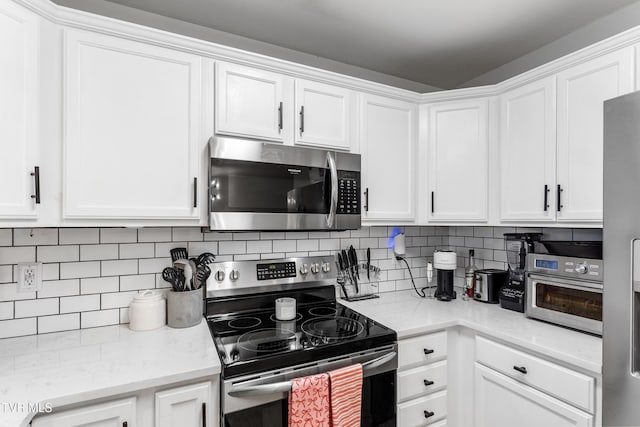 kitchen with stainless steel appliances, white cabinetry, and decorative backsplash