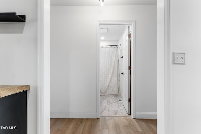 bathroom featuring a shower with shower curtain, baseboards, and wood finished floors