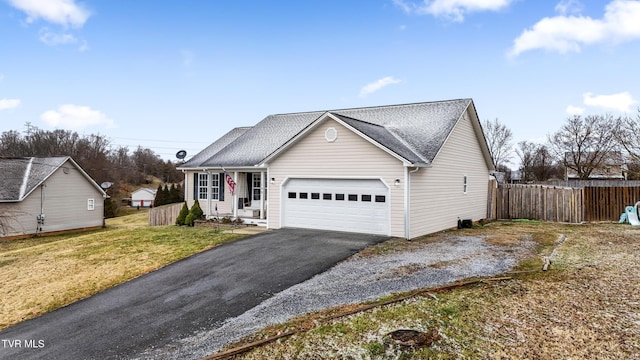 view of front of property with aphalt driveway, an attached garage, fence, and a front yard